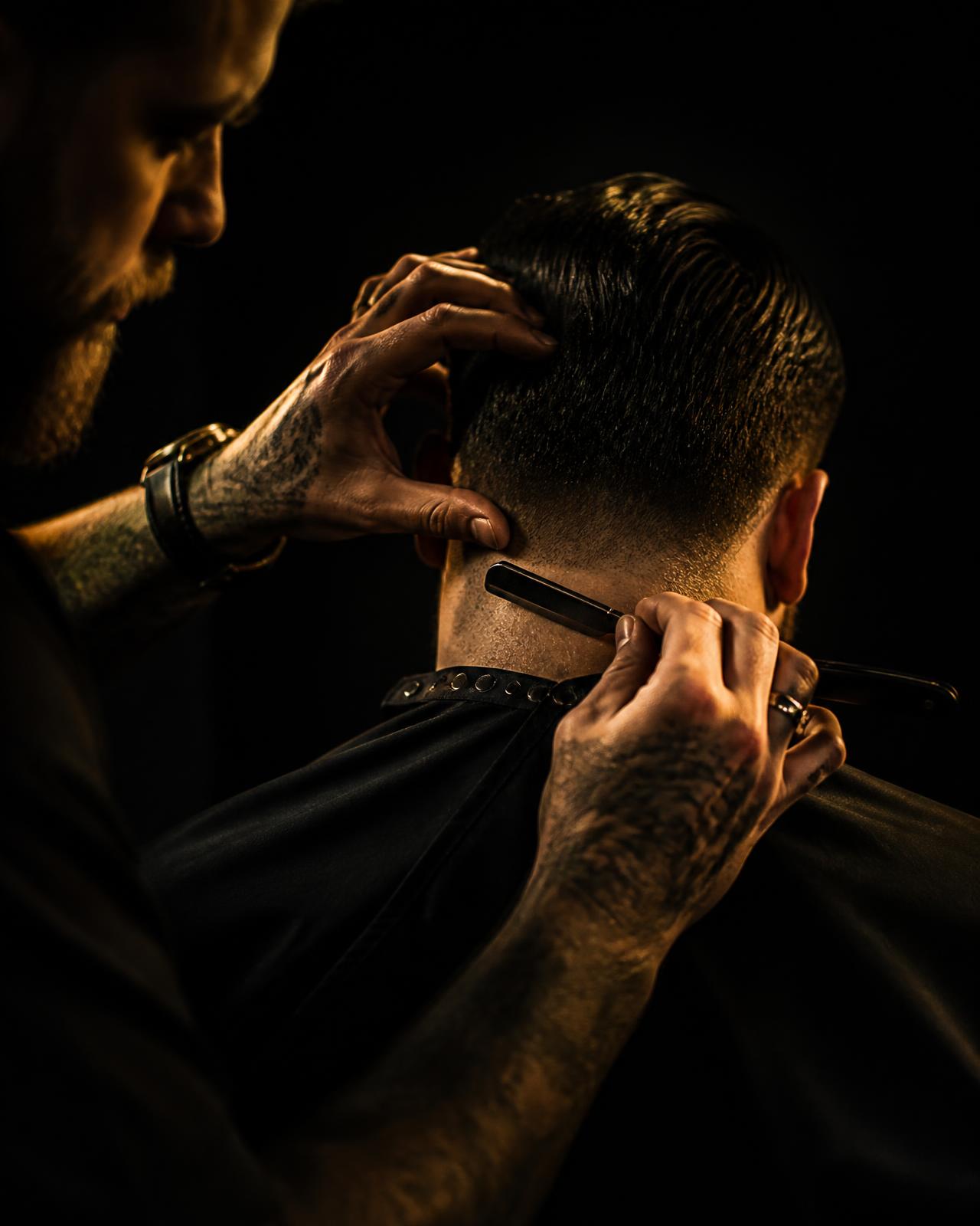 Barber using a straight razor to clean up a client's neckline